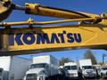 A yellow Komatsu PC55MR2 excavator with a prominent blue "KOMATSU" logo on the arm
