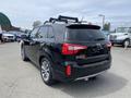 A black 2015 Kia Sorento with a roof rack viewed from the rear showing its distinctive taillights and sleek design