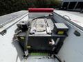 A large black tank with various hoses and valves mounted on a flatbed truck designed for holding and transporting liquids