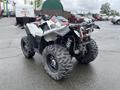 A 2017 Polaris Scrambler with a black and white body and large knobby tires is parked with its rear facing the viewer showcasing its suspension and exhaust system