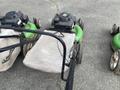 Three Honda Lawnboy mowers with green bodies and two Stihl line trimmers with black handles are arranged in a row