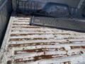 The image shows the inside of a truck bed with visible rust on the metal surface and a rubber mat positioned near the back