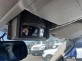 A 2013 Ford Expedition's interior rearview mirror reflecting the driver's hand holding a camera