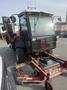 A red 2013 Toro Grounds Master 5910 with a cab and cutting deck attachments at the front and sides parked in an industrial area