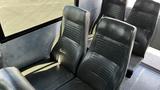 Interior seating of a 2014 Freightliner Thomas Diesel bus featuring black vinyl seats with vertical stripes and a spacious layout