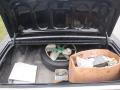 A 1974 Dodge Challenger trunk with a spare tire and a large bag containing various items including papers and a box