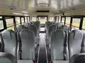 Interior view of a 2016 International CE300 school bus featuring rows of gray upholstered seats with safety belts and a central aisle