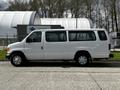 A white 2004 Ford Econoline van is parked facing the left with sliding doors and a simple design showing a clean exterior and standard wheels