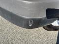 A close-up view of a scratched and scuffed rear bumper of a 2014 Chevrolet Express