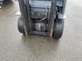 A 2011 Toyota 028FG15 forklift showing the front wheels and the underside of the chassis with visible hydraulic lines and motor components