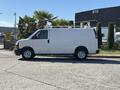 A white 2019 GMC Savana van with a high roof and metal ladder rack on top parked on a street