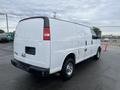 A 2014 Chevrolet Express van in white with a side view showing its rear and passenger doors and black trim on the roof and bumper