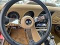 The interior of a 1970 Chevrolet Corvette featuring a leather-wrapped steering wheel with a logo a dashboard with round gauges and a gear shift in the center console