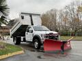 A 2021 Ford F600 dump truck with an elevated bed and a red snow plow attached to the front