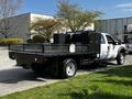 A 2016 Ford F-550 with a flatbed and a tool box attached on the back is parked, displaying its white body and black flatbed design