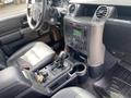 Interior of a 2006 Land Rover LR3 featuring a black dashboard with climate controls a radio and a gear shifter alongside leather seats and floor mats