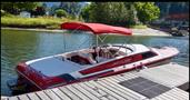 A 1989 Nordic Viking boat with a red and white exterior and a canopy is docked at the side of a body of water