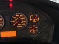 Close-up of a vehicle dashboard with speedometer, fuel gauge, and voltmeter displays illuminated in orange against a dark background