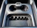 Center console of a 2019 RAM 1500 featuring two cup holders and a storage compartment with a textured surface