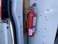 A red fire extinguisher secured to a wooden mount inside a vehicle