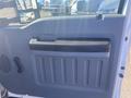Interior door panel of a 2014 Ford F-250 SD featuring a textured handle and storage compartment