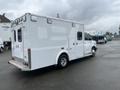 A 2016 Chevrolet Express, white with a boxy shape, featuring rear doors and lights, parked with a clear view of its side and rear sections