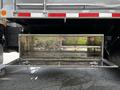 A silver toolbox mounted on the side of a 2010 Freightliner M2 106 with an open lid and visible interior markings