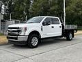 A white 2020 Ford F-350 pickup truck with a flatbed and chrome wheels parked on a street