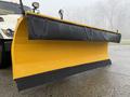 A yellow and black snow plow blade attached to a truck with mounting brackets visible on the sides