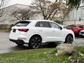 A white 2024 Audi Q3 with sporty black wheels parked on a grassy area showing its sleek design and modern features
