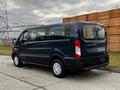 A blue 2020 Ford Transit van with sliding side doors and windows on the rear doors parked on a street