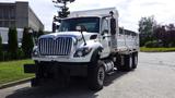 A 2014 International 7500 dump truck with a white cab and silver dump bed parked on a street