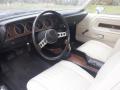 Interior of a 1974 Dodge Challenger featuring a black steering wheel with silver accents and white leather seats with horizontal stitching