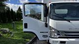 A 2016 Isuzu NPR truck with the driver's door open showcasing the cab and dashboard interior