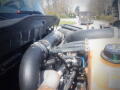 A close-up view of the engine and plumbing of a 2016 International WorkStar 7500 with various hoses and a coolant reservoir visible