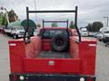 A red 2011 Ford F-250 SD pickup truck with a flatbed and a spare tire in the cargo area