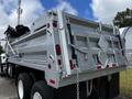 A silver 2017 International WorkStar 7600 dump truck with a raised bed and various vehicle lights and safety symbols on the back