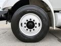Close-up of a black tire mounted on a white rim with visible lug nuts branding shows the tread pattern and size markings on the tire sidewall