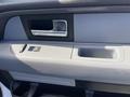 Interior door handle and control panel of a 2012 Ford F-150 featuring a chrome handle and buttons for window and door locking functions