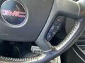 Close-up of a GMC Savana steering wheel with a logo and controls for audio and cruise settings visible on the side