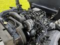 A close-up view of the engine compartment of a 2016 Isuzu NPR showing various components like the engine, hoses, and an alternator