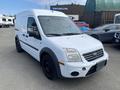 A white 2013 Ford Transit Connect van with a black front grille and wheels parked at a dealership