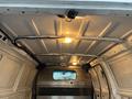 The interior of a 2011 Ford Econoline van showing the ceiling with overhead lights and a mesh partition visible at the rear end