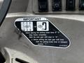 A close-up of a warning label on a tractor dashboard with instructions on using the parking brake and the main gear shift lever