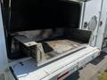 A 2004 Freightliner M2 truck with an open rear cargo compartment revealing a metal floor and sliding mechanism