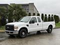 A white 2008 Ford F-250 SD pickup truck with a black grille and chrome accents parked on a roadway with a utility bed and black wheels