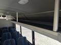 Interior view of a 2020 Chevrolet Express showing an overhead luggage rack with metal supports and patterned fabric seats below