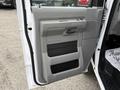 Close-up of a light gray door panel of a 2019 Ford Econoline featuring a handle speaker grill and storage compartments