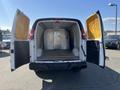 A 2013 Chevrolet Express cargo van with open rear doors revealing a spacious, empty interior and a metal partition visible inside