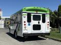 A white and green 2013 Chevrolet Express bus with a rear wheelchair access sign and a closed rear door